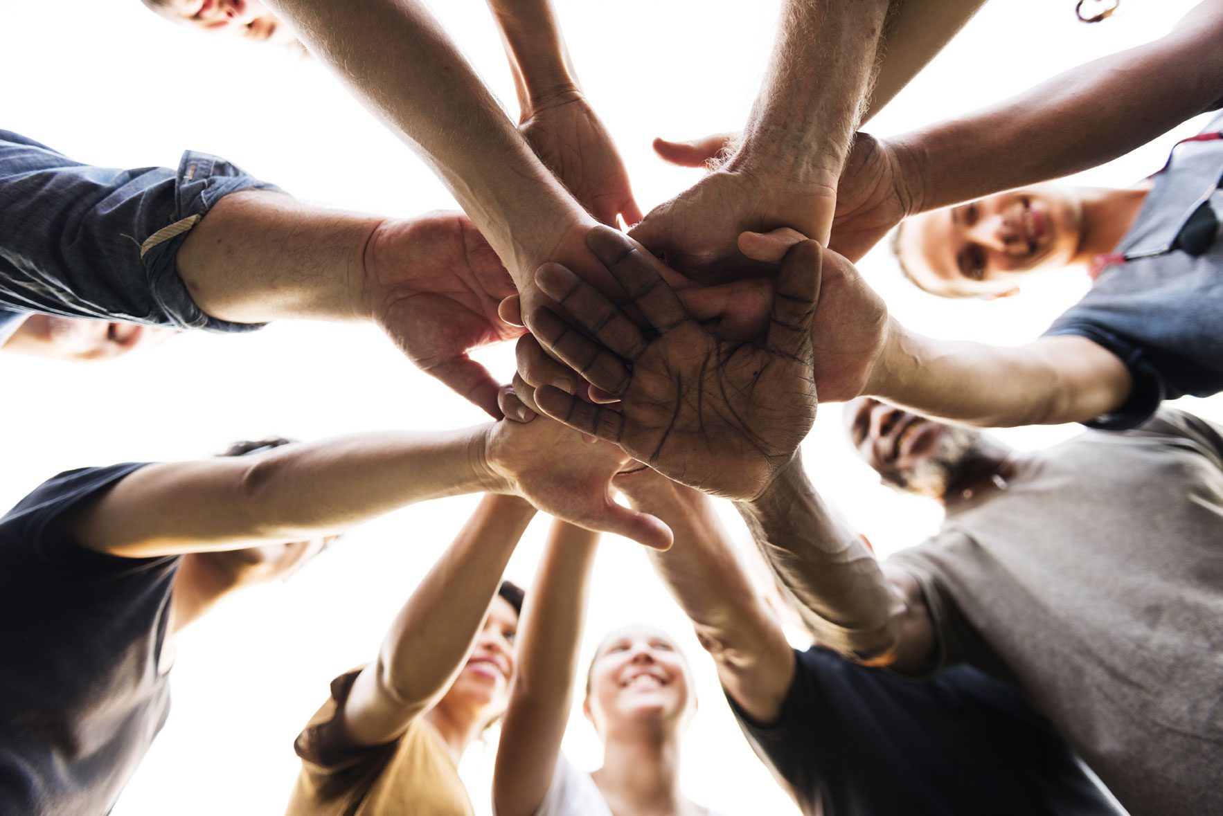Circle of people placing one hand in the centre